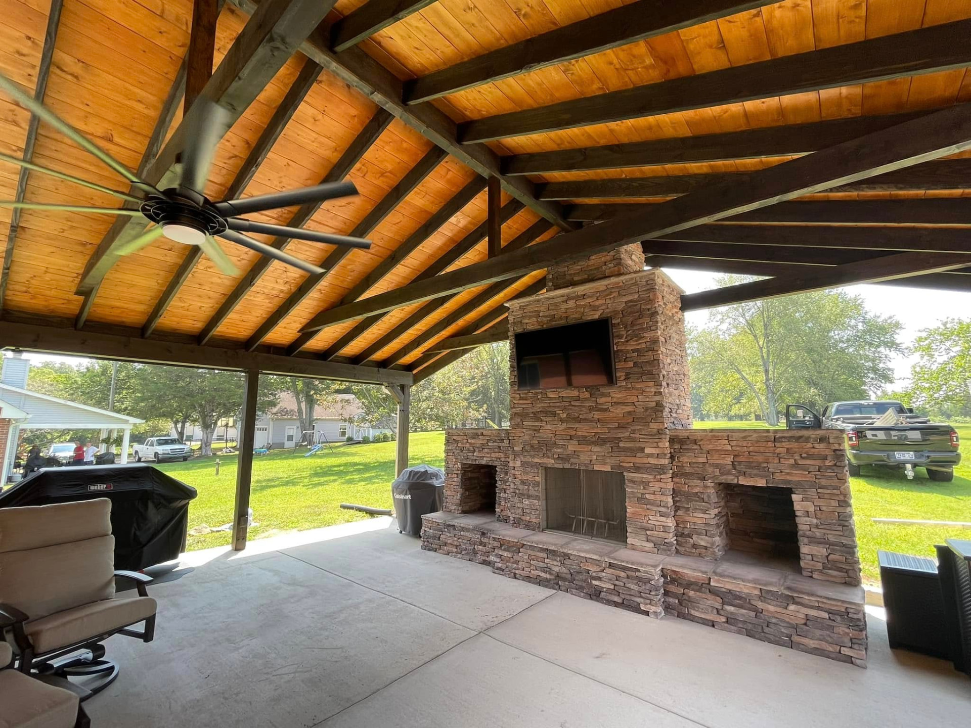 Covered Nashville patio with timber ceiling, exposed beams, and a stone fireplace